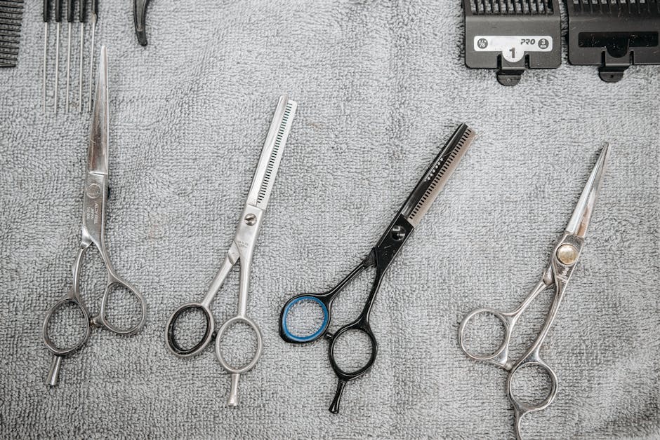 A set of professional haircutting scissors and tools neatly arranged on a grey towel.