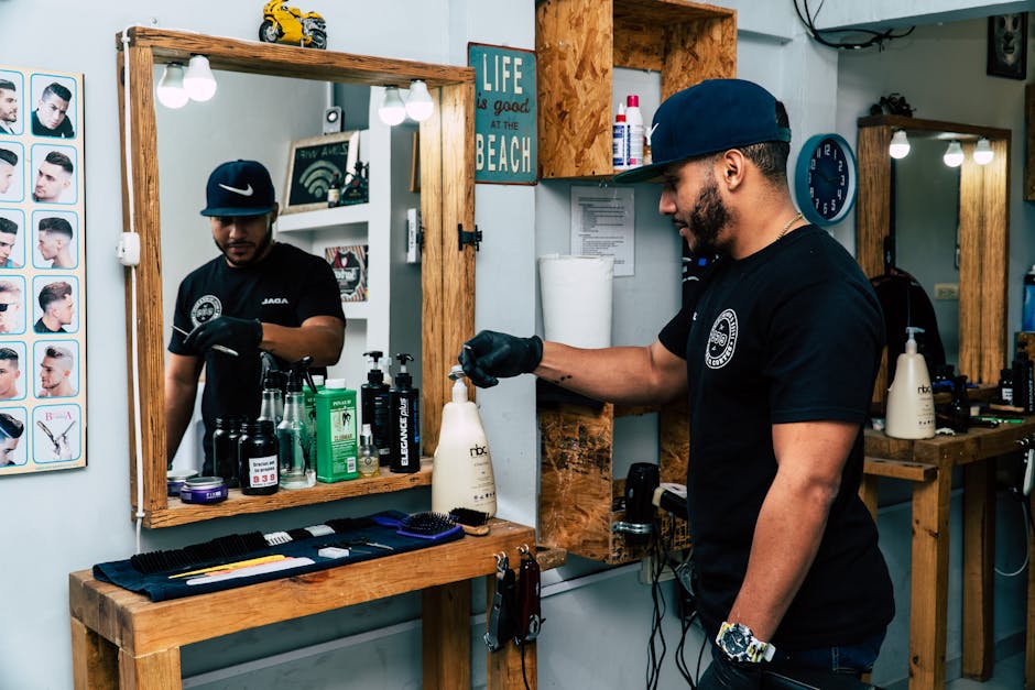 A barber in a stylish shop preparing tools for a haircut. Modern interior design with mirrors and grooming products.